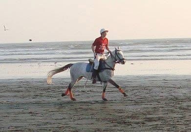 Rumman Shariq riding a polo pony on the beach.